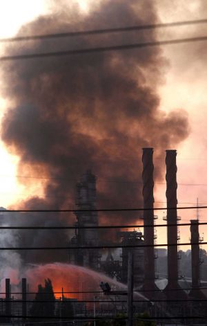 FILE - In this Aug. 6, 2012 file photo, fire crews pour water on a fire at the Chevron Richmond Refinery in Richmond, Calif., Officials have told residents of two Northern California cities to shelter-in-place as a fire at the refinery releases plumes of black smoke.   Richmond city leaders will hold a news conference Friday Aug. 2, 2013 to announce their lawsuit against Chevron over last year's refinery fire.  NORTHERN CALIFORNIA MANDATORY CREDIT PHOTOG & CHRONICLE; MAGS OUT; ; Photo: San Francisco Chronicle, Lance Iversen